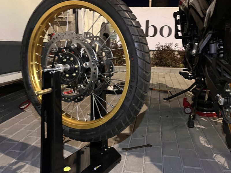 Koło motocyklowe ze złotą felgą szprychową na stojaku do wyważania statycznego, wieczorem