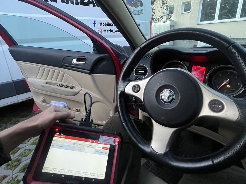 Ręka trzymająca tablet diagnostyczny we wnętrzu auta, za szybą stoi bus Mario